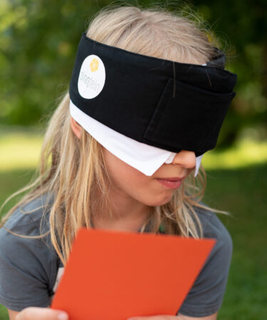 Kind mit oranger Karte und Maske