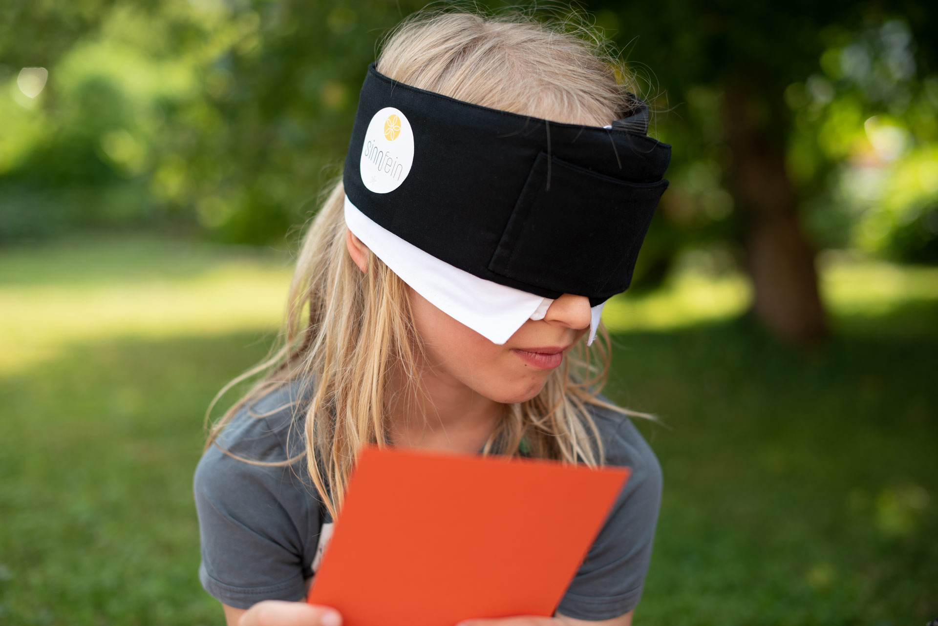 Kind mit oranger Karte und Maske